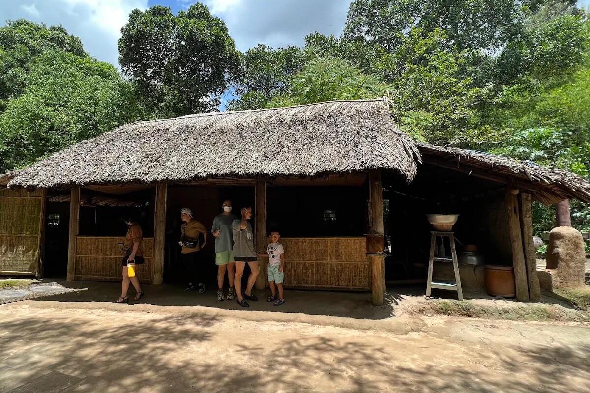Visitors exploring a traditional thatched hut at the Cu Chi Tunnels