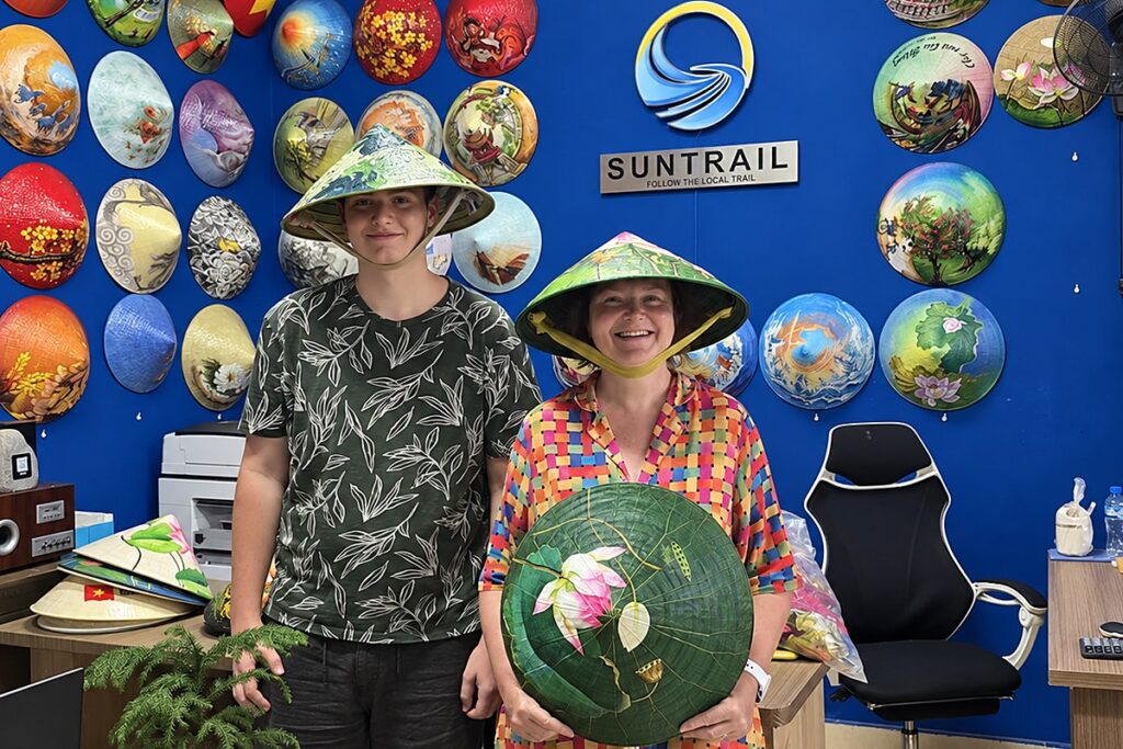 Couple holding their hand-painted conical hats at the Suntrail office in Ho Chi Minh City