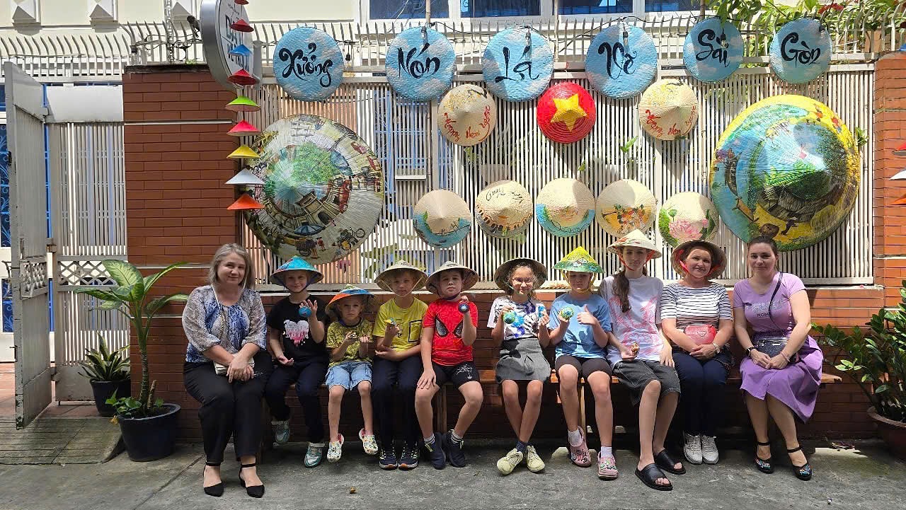 International families with children wearing their hand-painted conical hats after a workshop at the Suntrail Gallery in Ho Chi Minh City