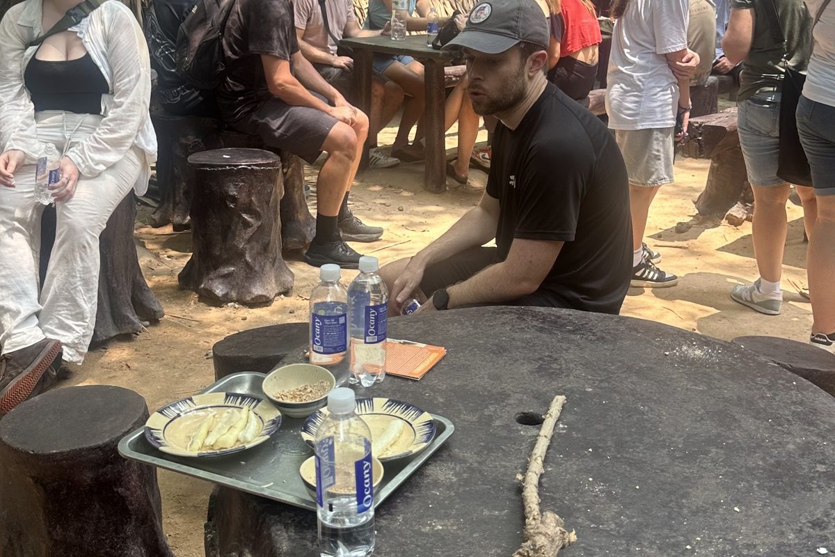 Morning vs full day Cu Chi tour: steamed cassava and tea served on a tree-stump table