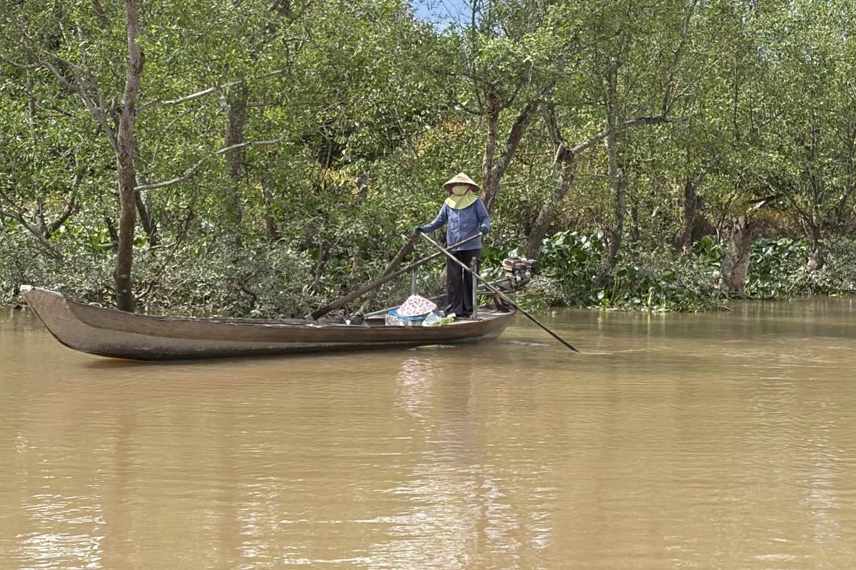 Can Tho city guide: woman in a conical hat rowing a sampan along a Mekong Delta canal